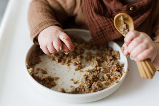 Cute baby infant eating complementary food close up in high chair. Family domestic life. Mom and son having dinner together. blw