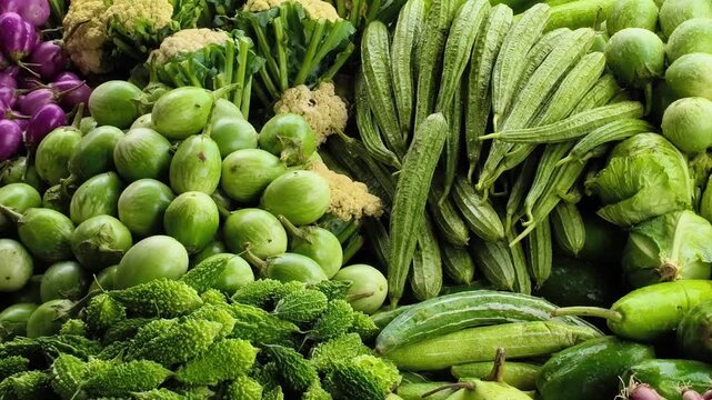 Colorful stack of fresh vegetables in a busy vegetable market. Eggplant, cauliflower, ridge gourd, pointed gourd, bitter melon, tomatoes, spinach, okra, beans, carrots, pumpkins