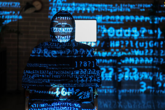 Hacker and projection of programming code in dark room