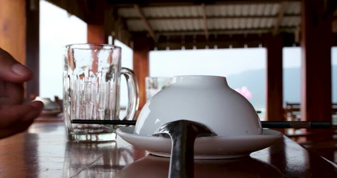 Table setup for hot pot on wooden table with upside-down bowls, Vietnamese spoons and empty glasses outdoors over water on Phu Quoc island Vietnam