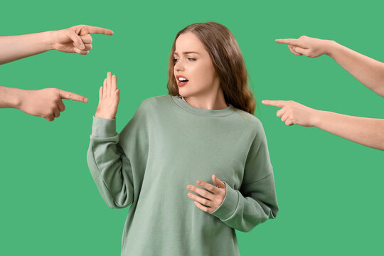 People pointing at young woman on green background. Accusation concept
