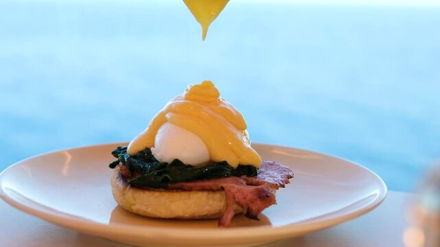 Poached egg sandwich drizzling sauce ocean background brunch European cuisine