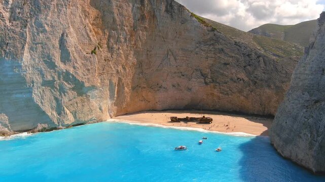 Aerial view of Navagio Beach shipwreck on white sand surrounded by high limestone cliffs and turquoise sea in Elatia, Greece.