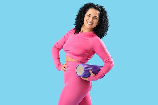 Sporty adult woman with body roller on blue background