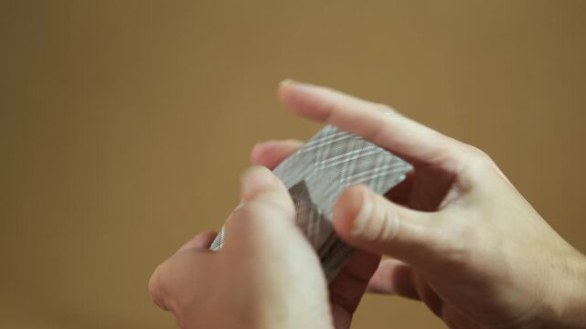Person shuffling deck of playing cards. Close up view of hands shuffling a deck of playing cards in preparation for a game or magic trick, mixing the deck for a fair deal