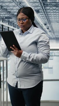 Vertical video Portrait of smiling woman in microchip factory developing advanced electronics automation process. Happy African american female engineer using EDA software to optimize semiconductor