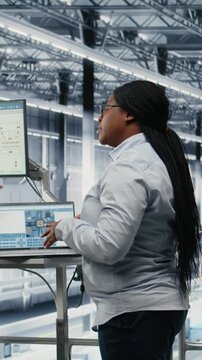 Vertical video Businesspeople team optimizes PCB smart factory workflow using EDA software on laptop. Employees using notebook simulation program tracking semiconductor production circuit layout