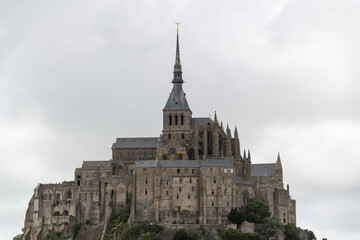 Fototapeta premium Mont Saint Michel abbey distant view with cloudy sky showing iconic historic French landmark architecture