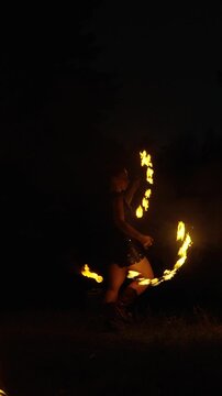 Dynamic nighttime fire dancing performance with swirling flames, skilled poi spinner movements, and dramatic silhouettes creating a captivating outdoor spectacle