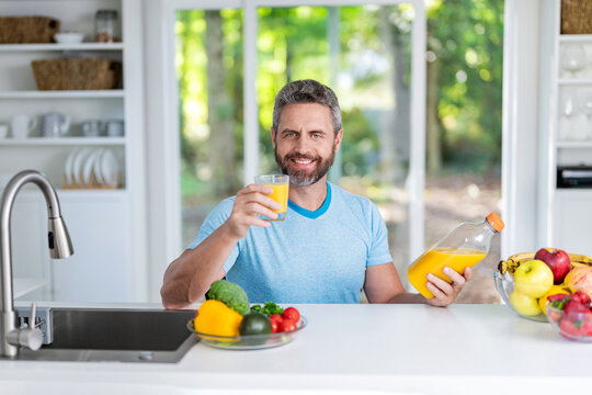 Morning at home. Breakfast in kitchen. Vitamin bottle. Man eating organic vegetable and juice for lunch. Enjoying healthy food. Man eat morning breakfast in kitchen. Mature man eating lunch