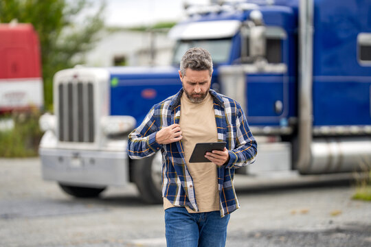 Truck maintenance. Hispanic trucker at truck. Using tablet chatting with customer. Service diagnostics for truck. Man use tablet to configure equipment. Automated logistics online internet