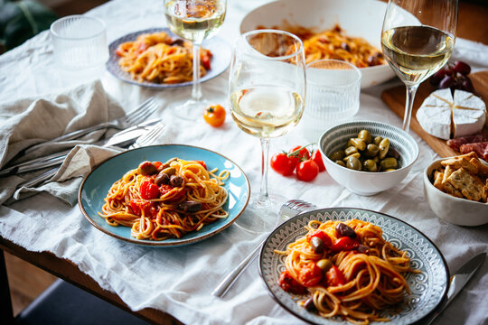 Friends having a pasta dinner with wine at home.