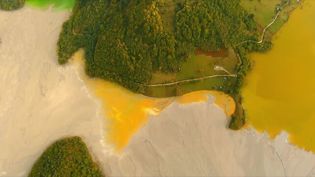 Aerial view of the toxic lake and sunken village with orange sludge and green hills in Geamana, Alba County, Romania.