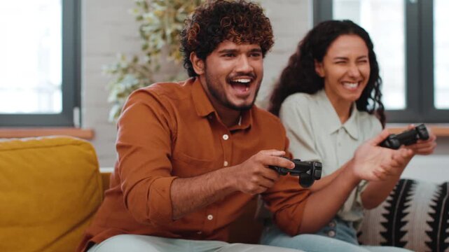 Two friends are playing video games together at home. They are laughing and focused on the screen while holding gaming controllers. The setting is cozy with a bright ambiance.