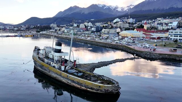 Static drone view of the historic Saint Christopher shipwreck grounded in Ushuaia harbor, featuring the city center and snow-capped Martial Mountains