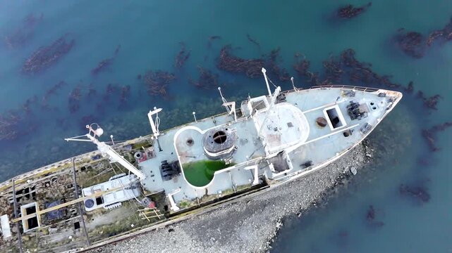 Cinematic drone pull-away with upward tilt, transitioning from a top-down view of the Saint Christopher wreck to a wide panorama of the Beagle Channel