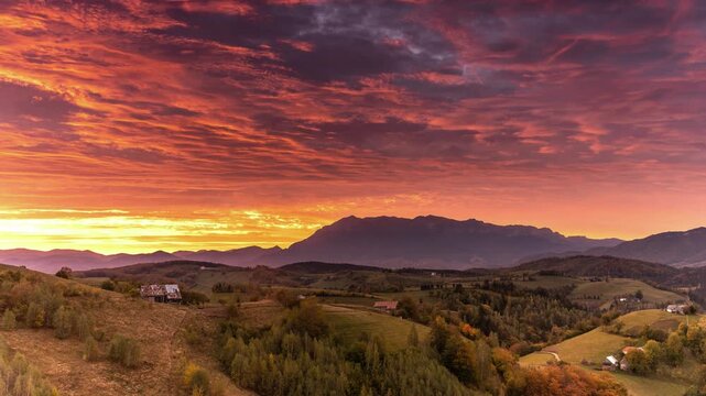 Aerial view of rolling hills and autumn forests under a dramatic sunset sky in Bran, Brasov, Romania.