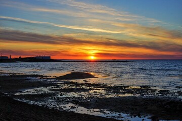 Fototapeta premium A picturesque view of the setting sun with clouds. A calm sunset over the Gulf of Finland, tinged with warm tones.