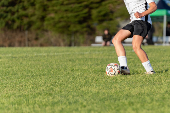 Soccer Player Dribbling Ball on Grass Field Outdoors