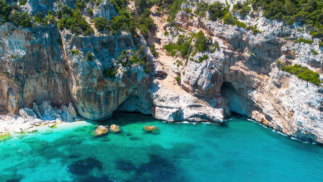 Aerial close-up of limestone caves and turquoise sea at Cala Mariolu beach, Gulf of Orosei, Sardinia, Italy