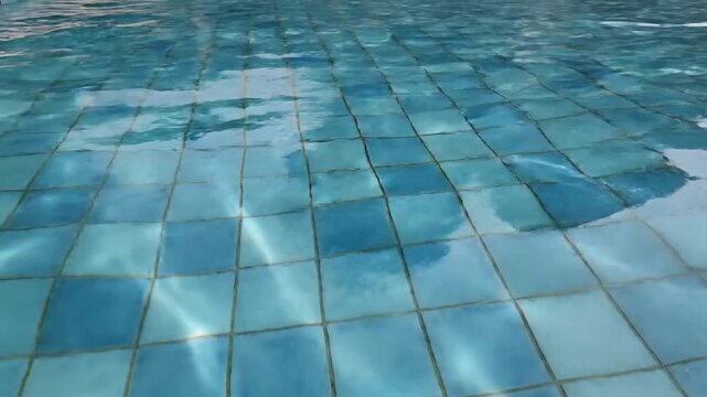 Close-up of shimmering pool water reflecting sunlight on tiled surface creating serene aquatic scene