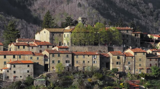 Aerial view of the historic stone village with its terracotta rooftops and church tower surrounded by the green forests of the Pratomagno mountains Trappola, Tuscany, Italy.