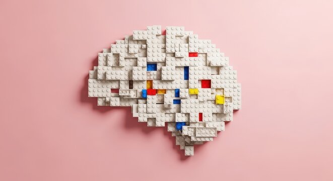 Human brain model constructed from interconnected plastic building blocks rests on a soft pink background.