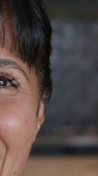 Vertical video: Smiling woman with lashes, bangs reacting to offscreen cue in room showing left eye