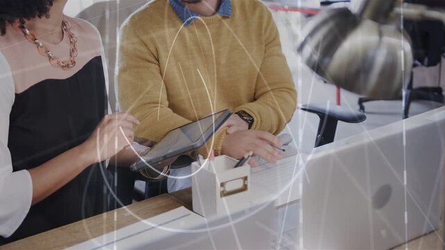 Woman presenting tablet, man tapping and reviewing business data while swirling overlay on glass