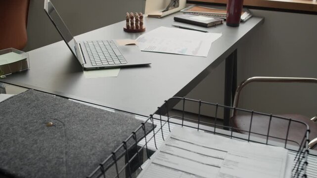 No people tilt down shot of cluttered workspace with laptop and stacks of docements near windowsill in office