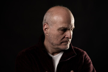 Obraz premium Mature man with stubble contemplating, captured in a low key studio setup