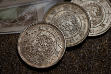 Close-up photo of the obverse of a Japanese 50 sen silver coin from the Meiji era, featuring the detailed dragon design, kanji inscriptions, and classic metallic texture. © Mr