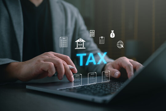 Businessman using laptop with virtual tax icons and invoice hologram. Concept of online tax payment, financial planning, income tax return, accounting, and corporate tax management systems.