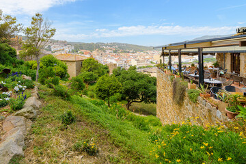 Fototapeta premium The terrace of a restaurant inside the walls of the 12th century castle, with views of the whitewashed village and sandy beach of Tossa de Mar, Spain.