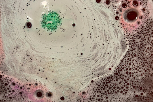 Foaming bubbles from bath bombs produce colorful spacy background plate