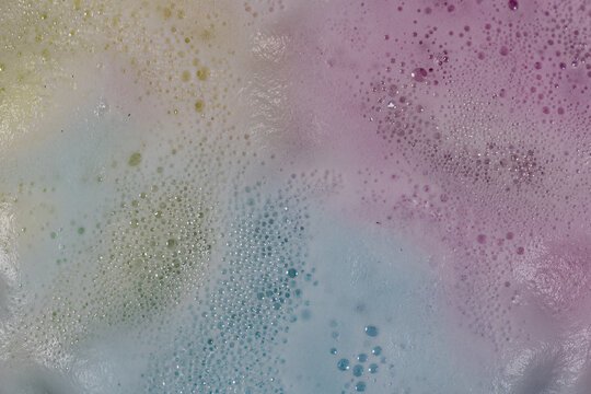 Sudsy foam from bath bombs creates colorful spacy background plate