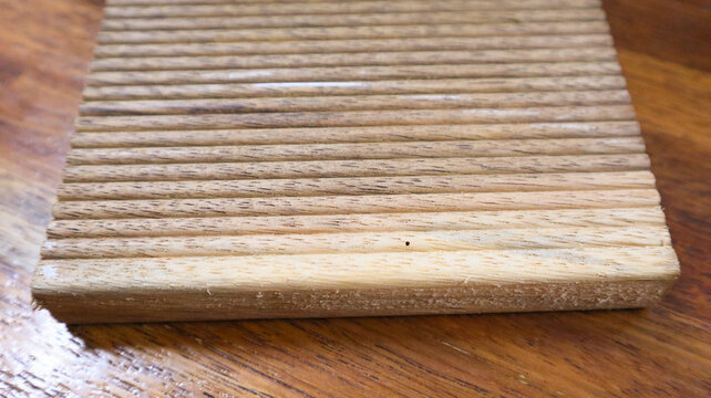 Close-up of grooved wooden board showing linear ridges, scattered grain marks, and tactile surface character shaped by craftsmanship