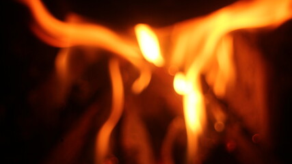 Fototapeta premium Burning log of firewood in fireplace. Close up abstract background Wood fire on black background