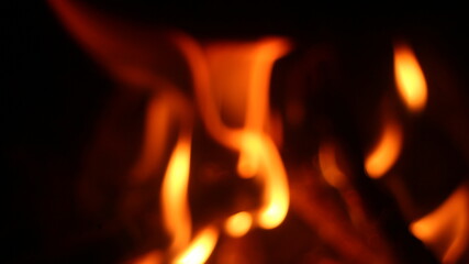 Fototapeta premium Burning log of firewood in fireplace. Close up abstract background Wood fire on black background