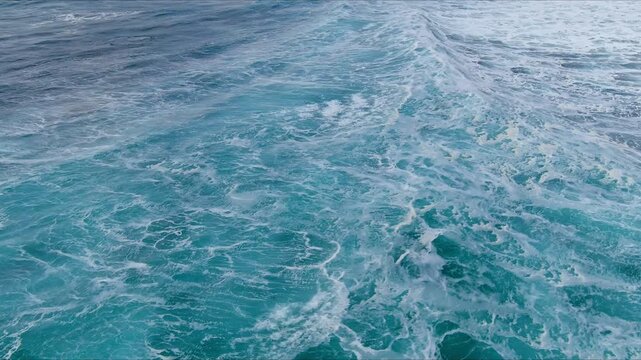Aerial view of churning turquoise ocean waves with white sea foam and ripples on the surface of the water in Nordland, Norway.