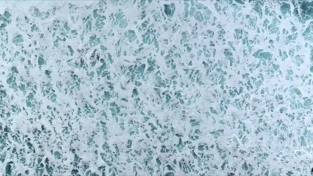 Aerial view of churning sea foam and turquoise ocean waves crashing in the sea Nordland, Norway.