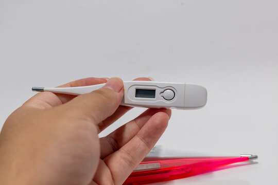 Hand holding a digital clinical thermometer for body temperature measurement.