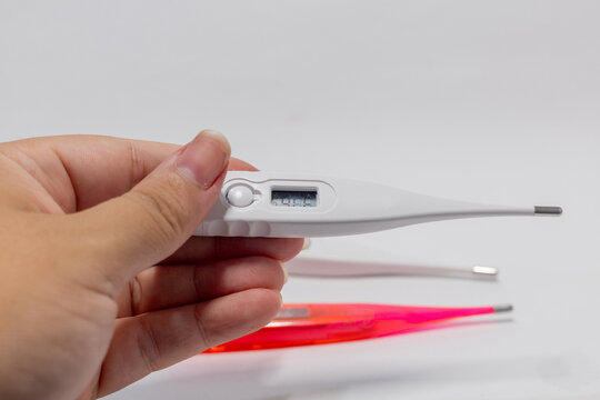 Hand holding a digital clinical thermometer for body temperature measurement.