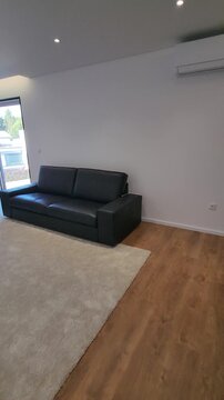 Camera moving through living room with sofa, wooden floor and carpet and light wall. Real estate walkthrough showing interior layout, residential space, minimal design and home presentation.