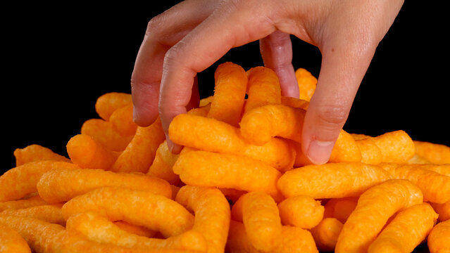 Human Hand Reaching into a Pile of Orange Cheese Puffs