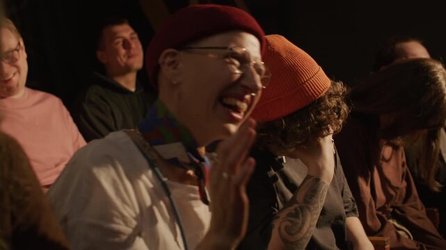 Young audience members listening to hilarious jokes and guffawing during live stand up show performed by comedian in club