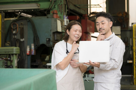 工場経営ででノートパソコンを確認する夫婦のDX活用、itやAI化の業務効率化で困る迷う、悩む考えるイメージ　どうしようかな～
