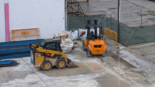 Palma de Mallorca, Spain &ndash; May 15, 2025: Caterpillar CAT skid steer loader and Mast Explorer forklift at construction site. Heavy machinery, industrial area, logistics, material handling, equipment.