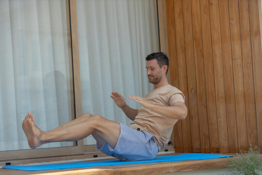 Focused man doing core exercise for fitness at home. His active, healthy lifestyle includes challenging abdominal workout on mat outdoor for strong body balance and wellness
