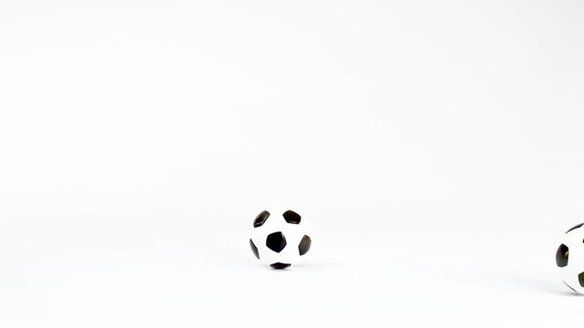 Miniature Soccer Balls Rolling and Bouncing on a White Background